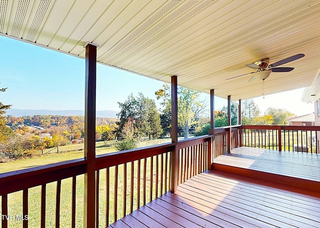 deck with a yard, ceiling fan, and a mountain view