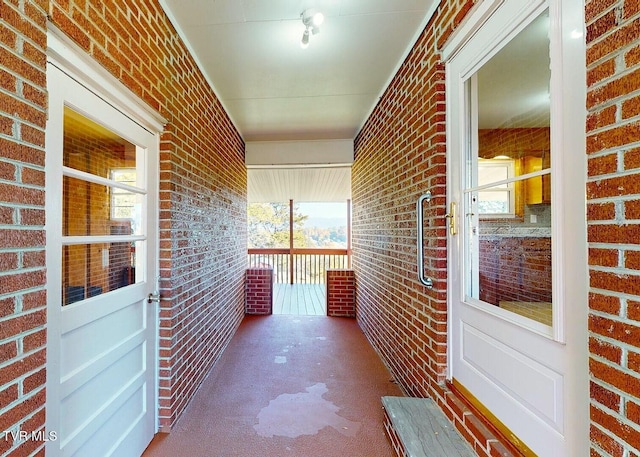 interior space featuring brick wall and dark colored carpet