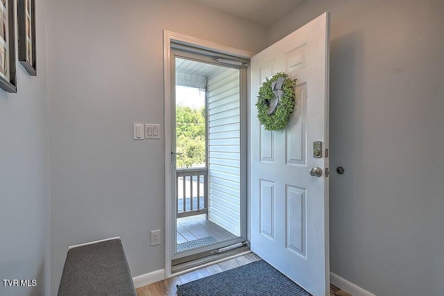 doorway with baseboards and light wood-style flooring