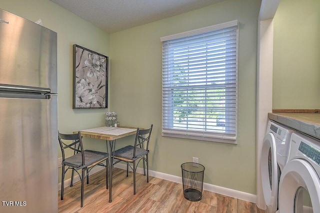 dining space featuring baseboards, a textured ceiling, wood finished floors, and washer and dryer