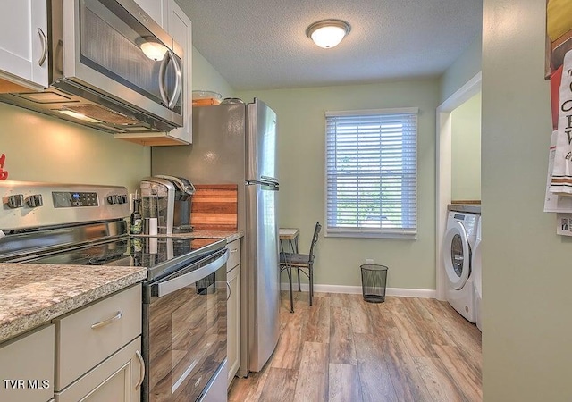 kitchen with white cabinetry, appliances with stainless steel finishes, light wood-style flooring, and washer / dryer