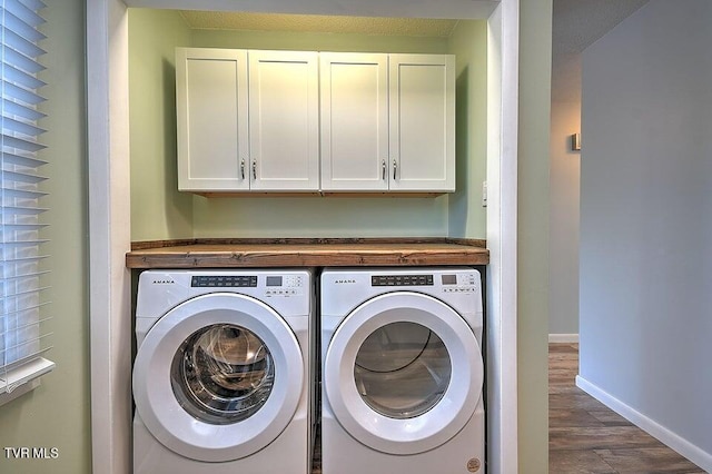 clothes washing area with washing machine and clothes dryer, baseboards, dark wood-type flooring, and cabinet space