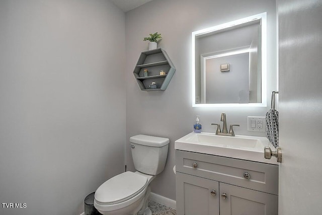 bathroom featuring toilet, baseboards, and vanity