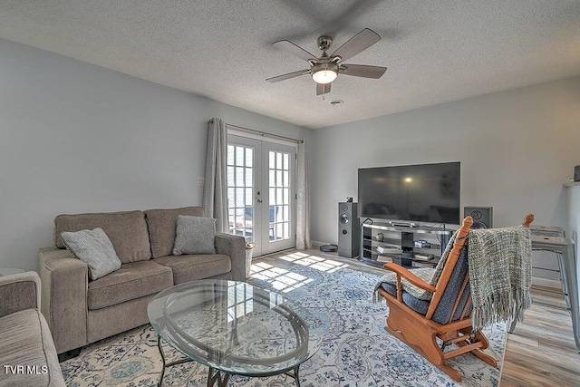 living room featuring a ceiling fan, french doors, a textured ceiling, and wood finished floors