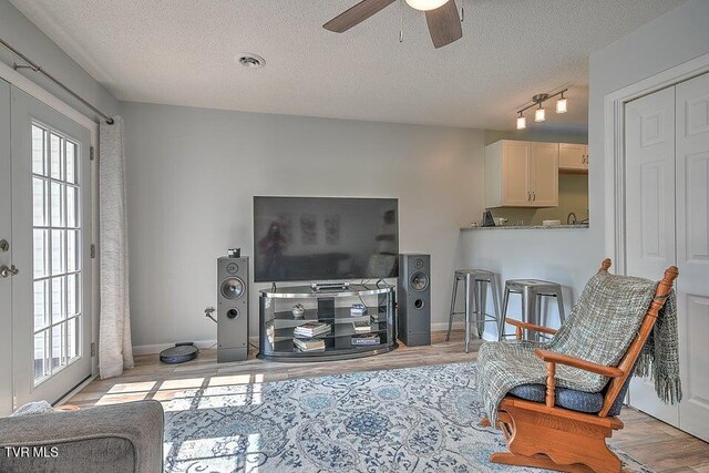 living room with a textured ceiling, ceiling fan, and a healthy amount of sunlight