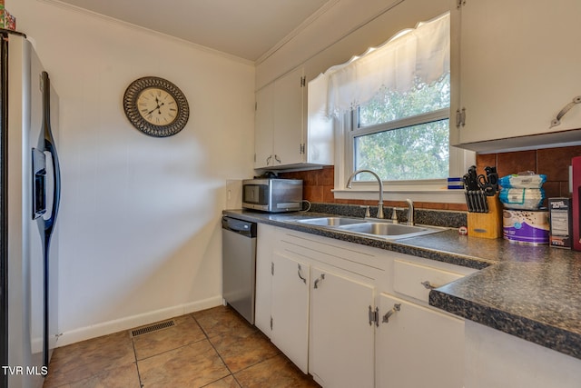 kitchen featuring tile patterned floors, ornamental molding, appliances with stainless steel finishes, sink, and white cabinets