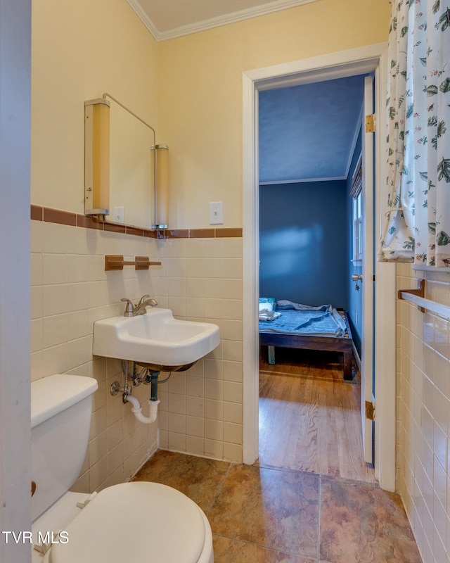 bathroom featuring sink, ornamental molding, hardwood / wood-style floors, toilet, and tile walls