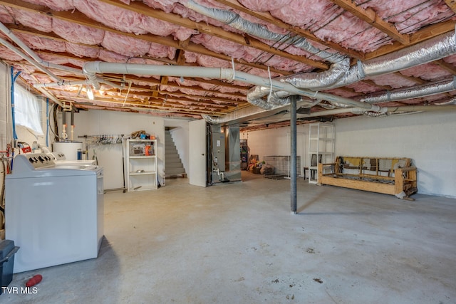 basement featuring electric water heater, heating unit, and washer and clothes dryer