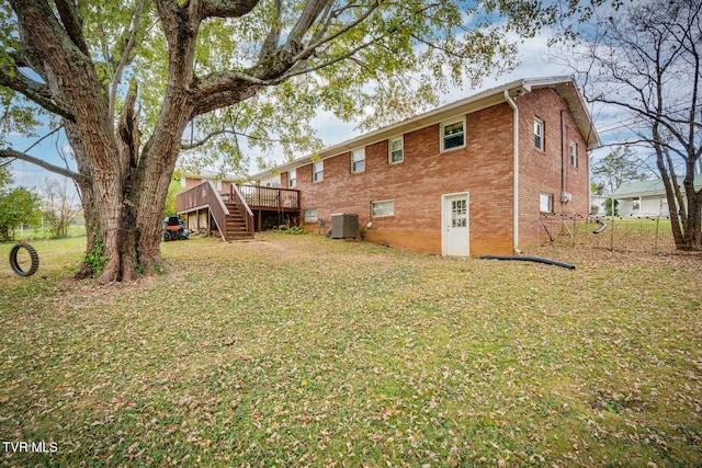 back of property with a deck, a lawn, and central AC