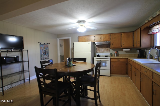 939 Muddy Creek Rd, Piney Flats, TN 37686 - kitchen featuring white appliances, under cabinet range hood, light wood-style floors, brown cabinets, and a textured ceiling