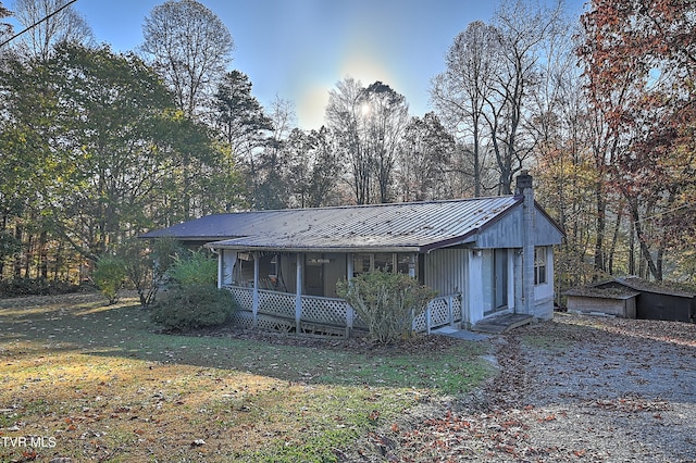 view of front facade with an outbuilding, a porch, and a front lawn