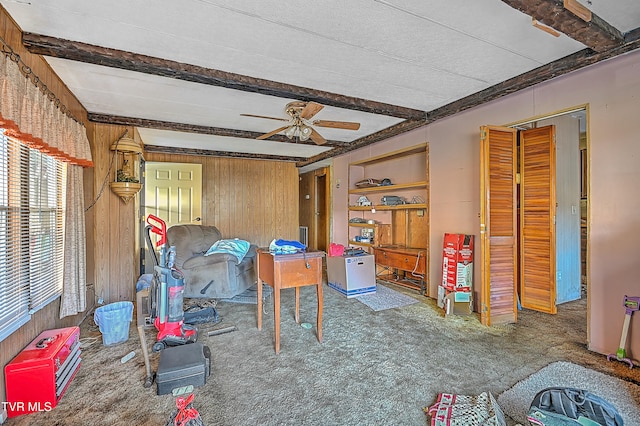 playroom featuring ceiling fan, beamed ceiling, wooden walls, and carpet