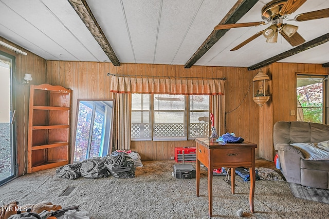 interior space featuring a textured ceiling, wooden walls, ceiling fan, and beam ceiling