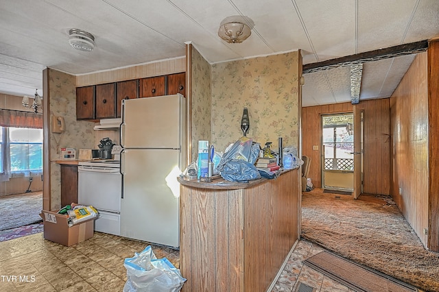 kitchen with wood walls, white appliances, a textured ceiling, and beam ceiling