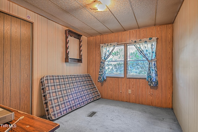 bedroom featuring wooden walls and carpet flooring