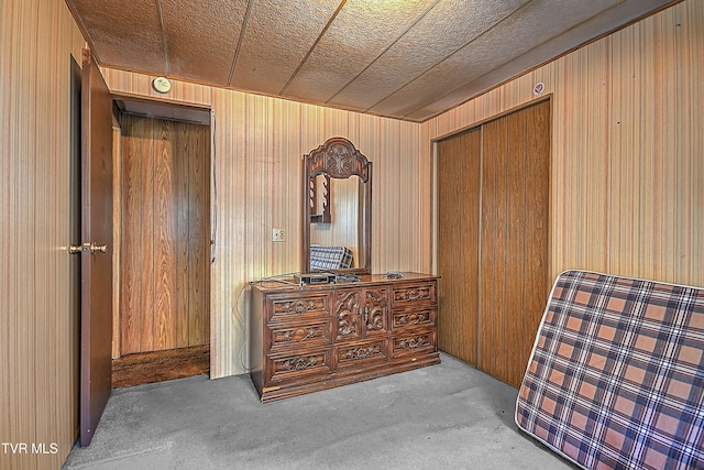 sitting room featuring a textured ceiling, light colored carpet, and wooden walls