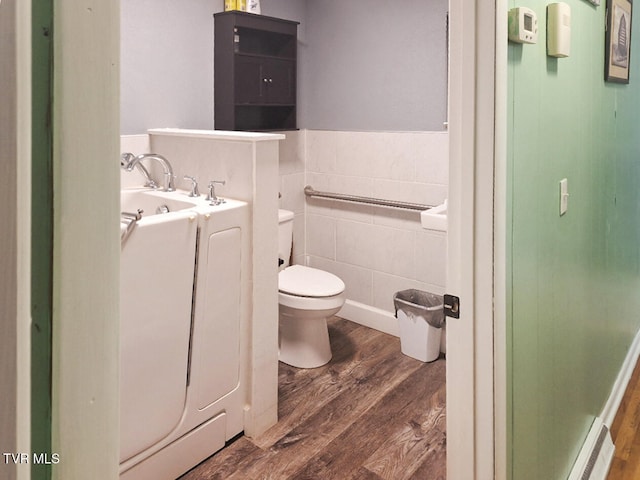 bathroom featuring a relaxing tiled tub, hardwood / wood-style flooring, toilet, and a baseboard radiator