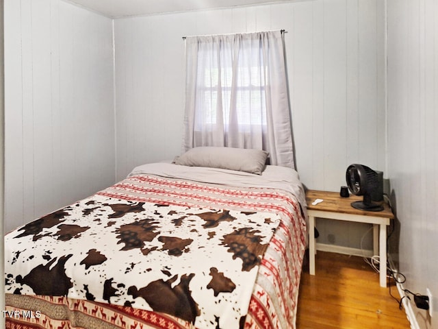 bedroom with wood walls and hardwood / wood-style flooring