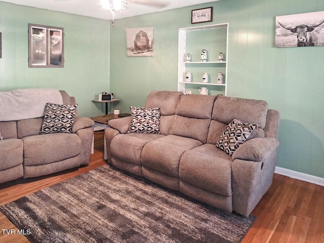 living room with built in shelves and wood-type flooring