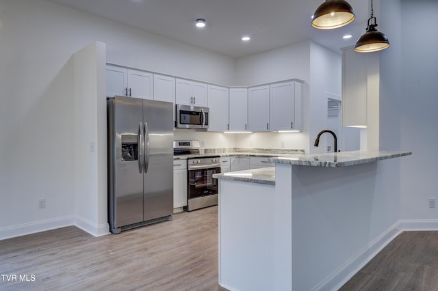 kitchen featuring kitchen peninsula, stainless steel appliances, white cabinetry, and light stone countertops