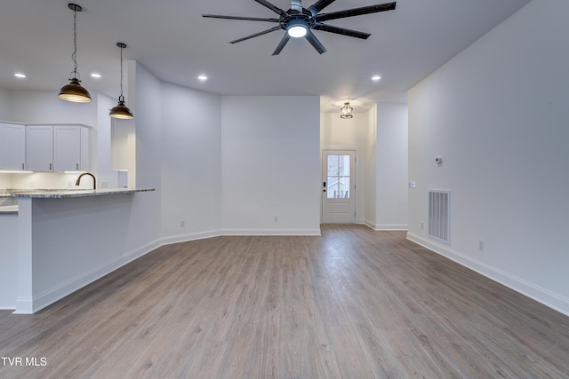 unfurnished living room with ceiling fan, light hardwood / wood-style floors, and sink