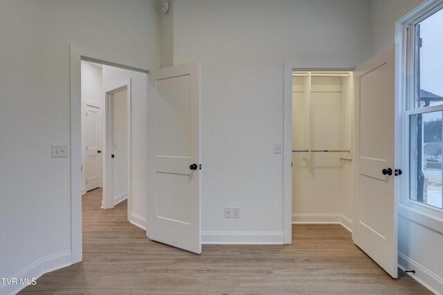 unfurnished bedroom featuring light wood-type flooring, multiple windows, and a closet