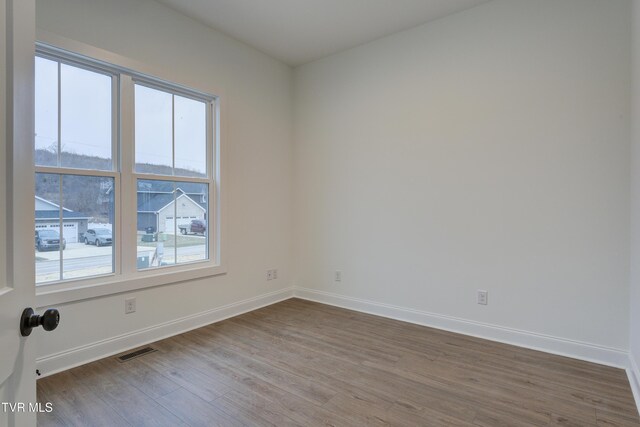 empty room with hardwood / wood-style floors and plenty of natural light