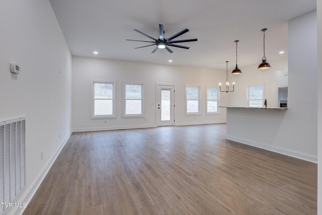 unfurnished living room featuring wood-type flooring, ceiling fan with notable chandelier, and sink