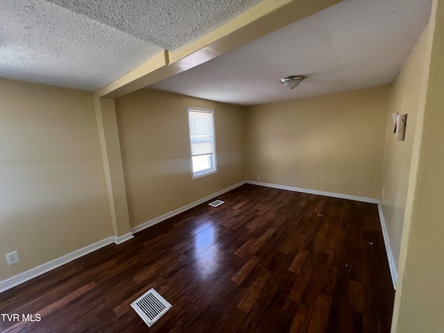 empty room featuring a textured ceiling and dark hardwood / wood-style flooring