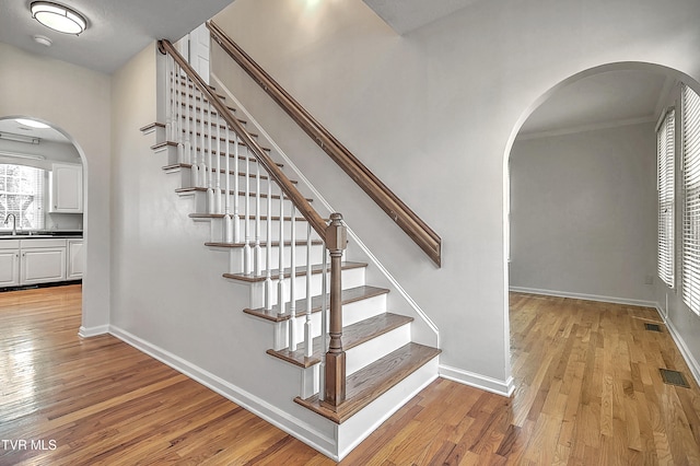 stairs featuring wood-type flooring and sink