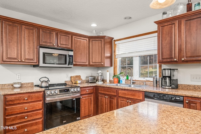 kitchen with light stone countertops, sink, stainless steel appliances, and a textured ceiling