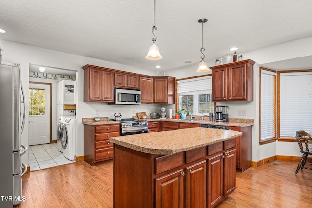 kitchen with a healthy amount of sunlight, a center island, stainless steel appliances, and light wood-type flooring