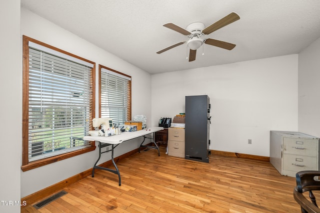 office featuring ceiling fan, light hardwood / wood-style floors, and a textured ceiling