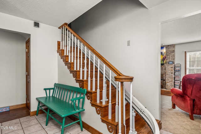 staircase with a textured ceiling and tile patterned floors