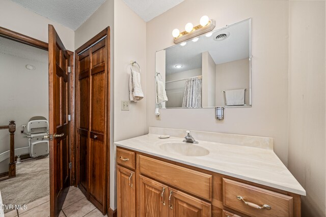 bathroom with vanity, a textured ceiling, and tile patterned flooring