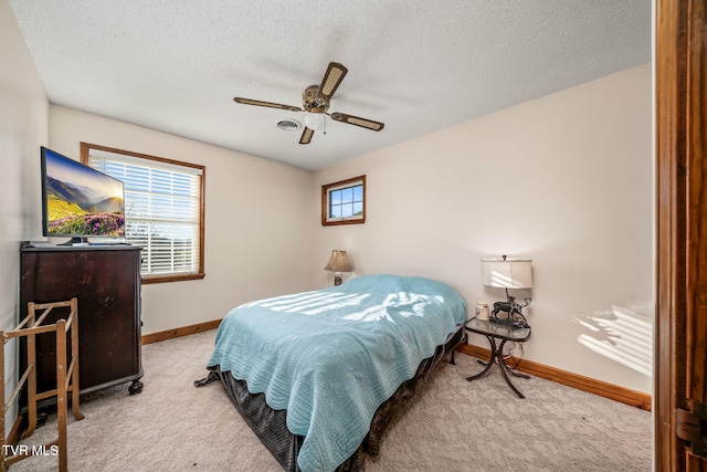 bedroom with a textured ceiling, light colored carpet, and ceiling fan