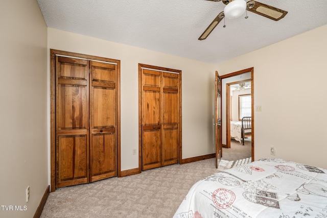 carpeted bedroom featuring a textured ceiling, two closets, and ceiling fan