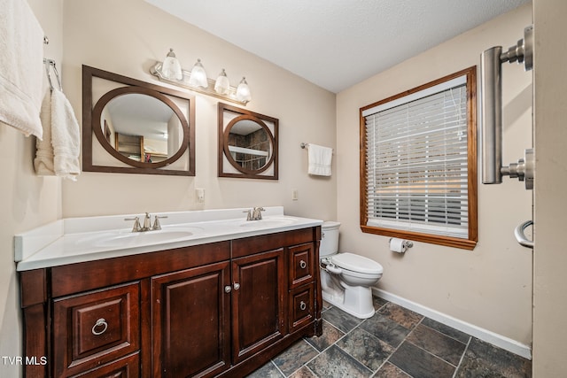 bathroom with a textured ceiling, vanity, and toilet