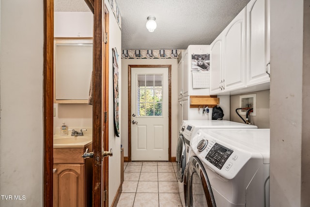 laundry area with cabinets, a textured ceiling, sink, light tile patterned floors, and independent washer and dryer