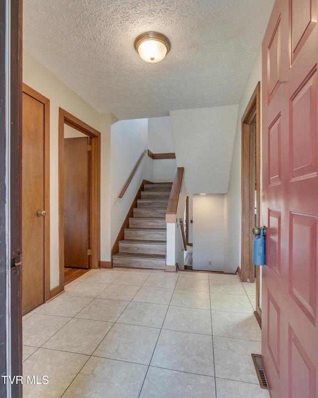 entryway with a textured ceiling and light tile patterned flooring