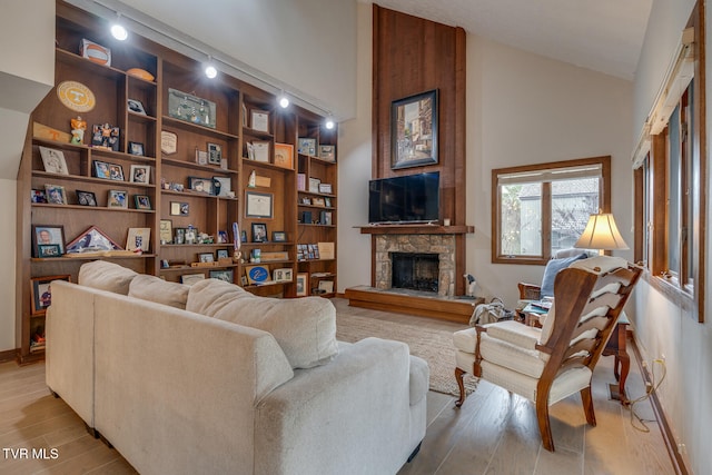 living room with high vaulted ceiling, light hardwood / wood-style floors, and a fireplace