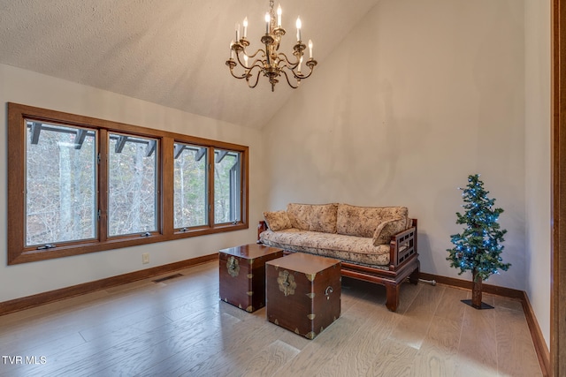 living room with hardwood / wood-style floors, a notable chandelier, a textured ceiling, and high vaulted ceiling