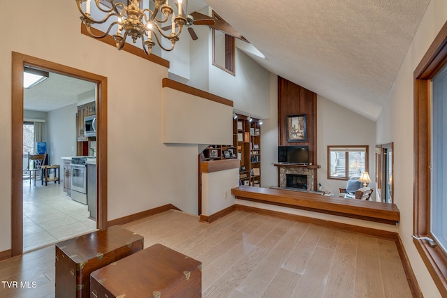 living room with high vaulted ceiling, a wealth of natural light, a textured ceiling, and light hardwood / wood-style floors