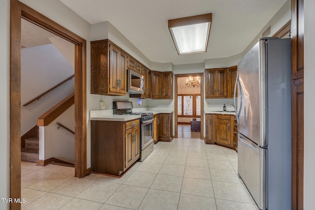 kitchen featuring sink, a notable chandelier, light tile patterned flooring, and stainless steel appliances