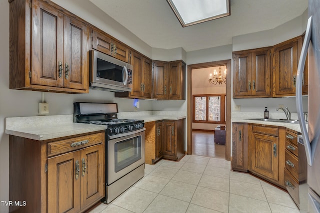 kitchen with light tile patterned floors, stainless steel appliances, sink, and an inviting chandelier