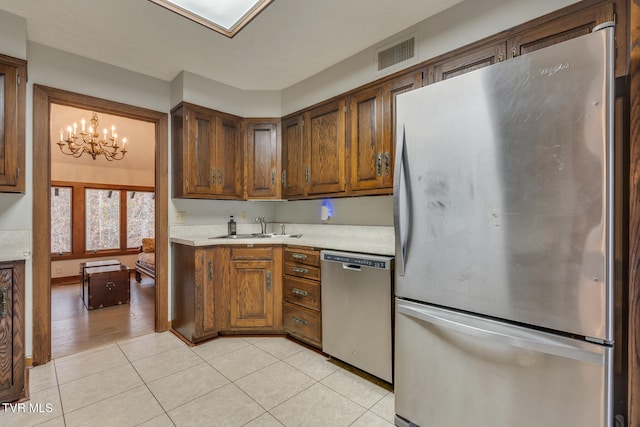 kitchen featuring stainless steel appliances, sink, light hardwood / wood-style flooring, and a notable chandelier