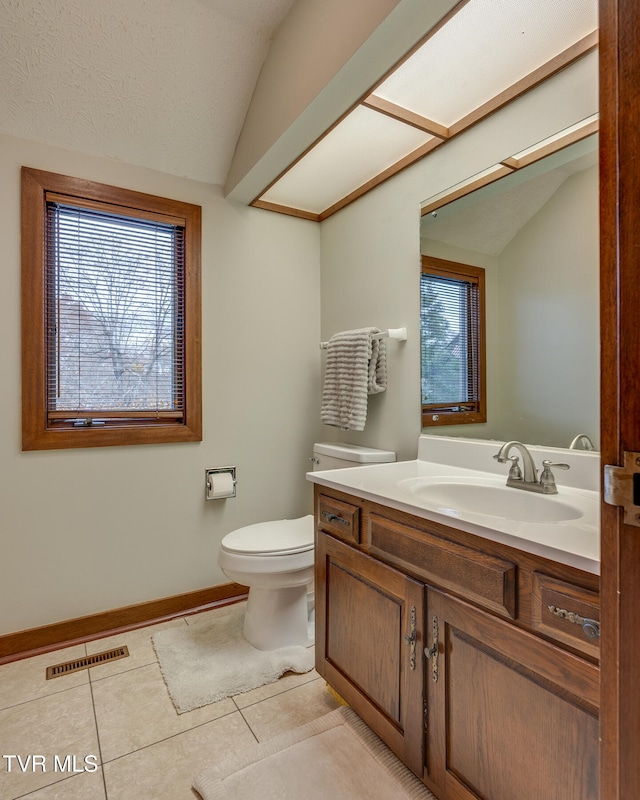 bathroom featuring tile patterned floors, toilet, vaulted ceiling, a textured ceiling, and vanity