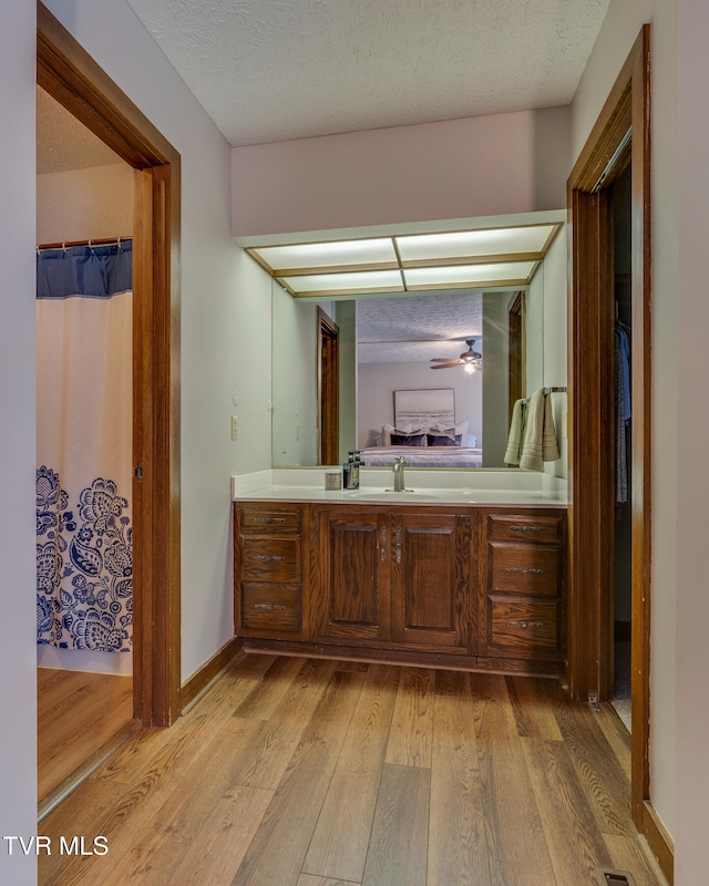 bathroom featuring walk in shower, vanity, a textured ceiling, hardwood / wood-style floors, and ceiling fan