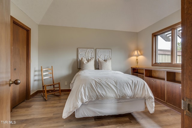 bedroom featuring light wood-type flooring and lofted ceiling