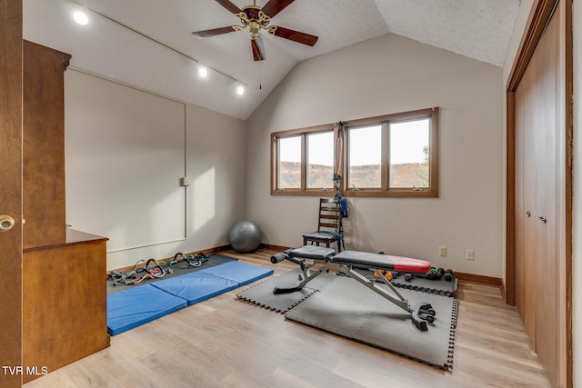 exercise room with ceiling fan, vaulted ceiling, light hardwood / wood-style floors, and a textured ceiling